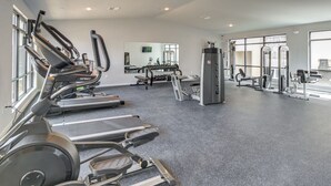 Un gimnasio con cintas de correr, máquinas de pesas y un espejo grande.