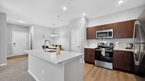 Una cocina moderna con una isla central, electrodomésticos de acero inoxidable y armarios de madera.