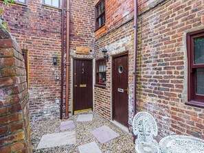 A narrow alleyway with a brick building, a wooden door, and a white metal bench. - Waterfront Stay for Two (Whitby)