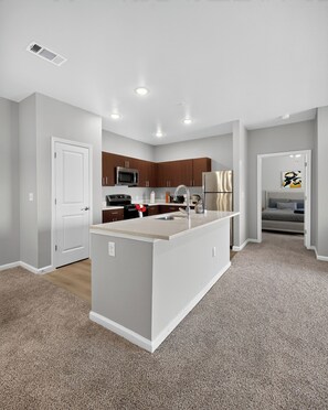 A modern kitchen with a central island, stainless steel appliances, and wooden cabinets.