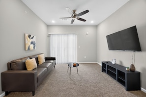 Ein Wohnzimmer mit Sofa, Couchtisch, Fernseher und Deckenventilator.