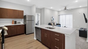A modern kitchen with wooden cabinets, stainless steel appliances, and a large island with a sink. - Whitewing Flats Retreat (Princeton)