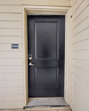 A black door with a number plate '7304' and a metal step leading up to it. - Whitewing Flats Spacious 2BR (Princeton)