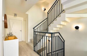 A modern staircase with a black railing, a white door, and a wall-mounted light fixture. - Golden View 2472 Private Pool & Jacuzzi (Manilva)