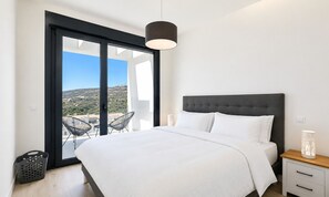 Ein Schlafzimmer mit Bett, Nachttisch, Lampe und Blick ins Freie.