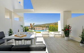 A modern outdoor patio with a pool, seating, and potted plants.