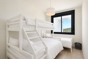A bunk bed room with a window and a hanging light fixture.