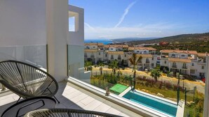 En balkon med udsigt over et boligområde, en swimmingpool og en stol.