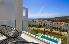 A balcony with a view of a residential area, a pool, and a chair. - Golden View 2472 Private Pool & Jacuzzi (Manilva)