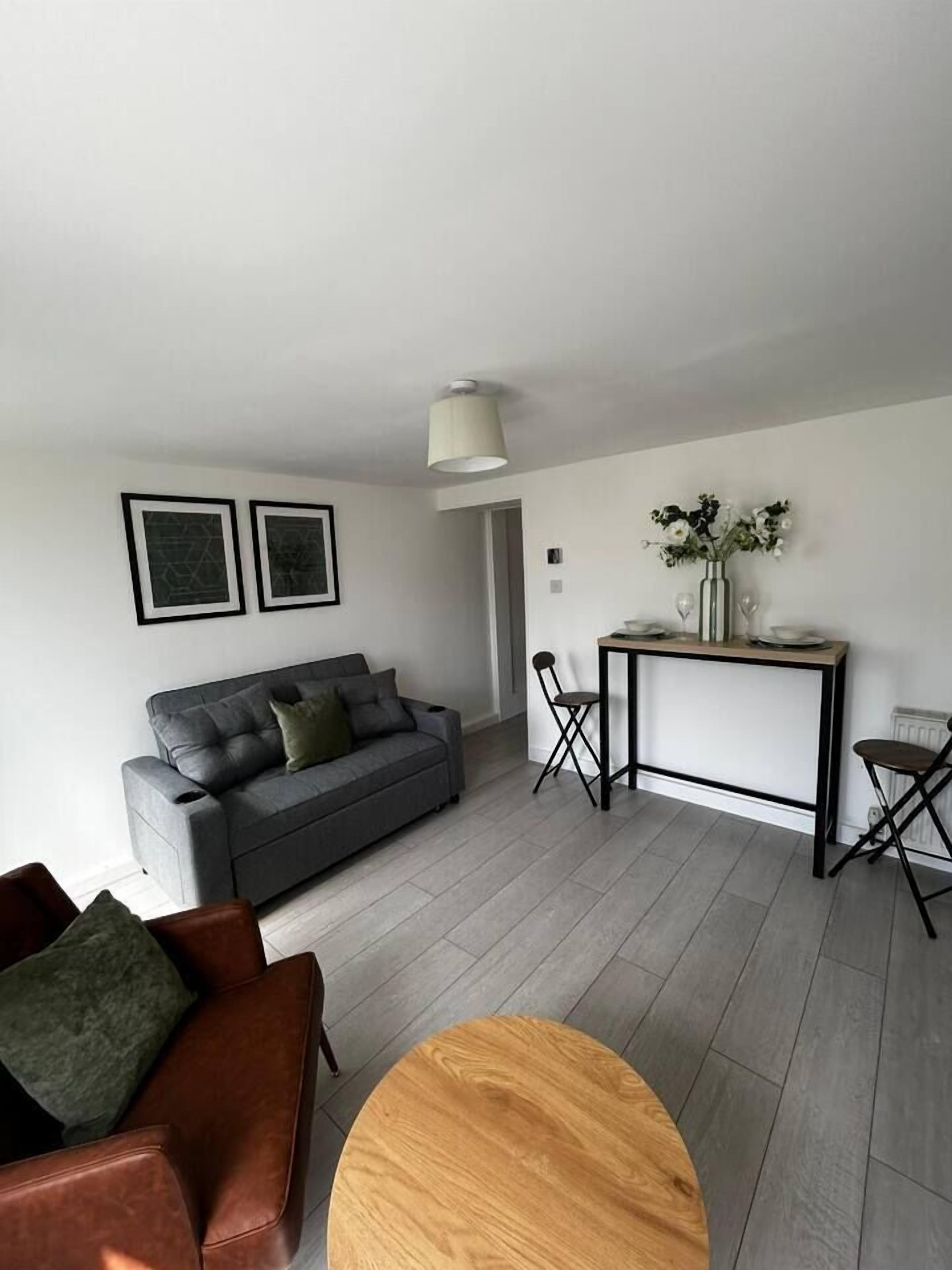 A modern living room with a grey sofa, a wooden coffee table, and a dining area with a table and chairs.