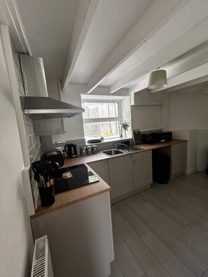 Een kleine keuken met raam, een inbouwfornuis en een spoelbak.