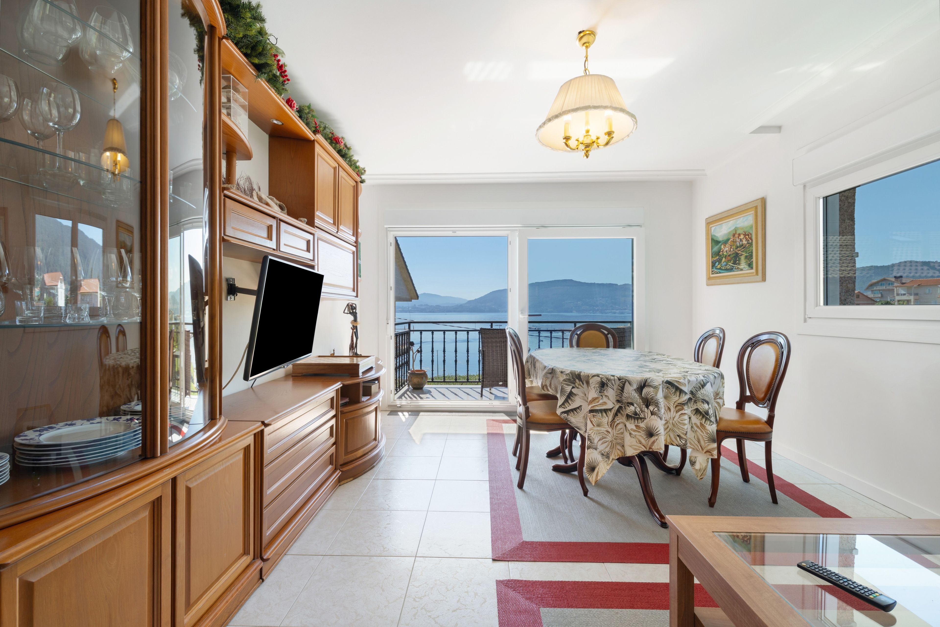 Una cocina moderna con comedor, televisor y vista al mar.