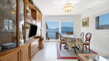 Una cocina moderna con comedor, televisor y vista al mar.