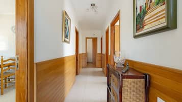 Un couloir aux murs lambrissés, un coin repas avec une table et des chaises en bois, et un escalier menant à un autre niveau.