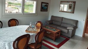 Ein Essbereich mit Tisch für vier Personen, einer Couch und einer Kristallleuchter.