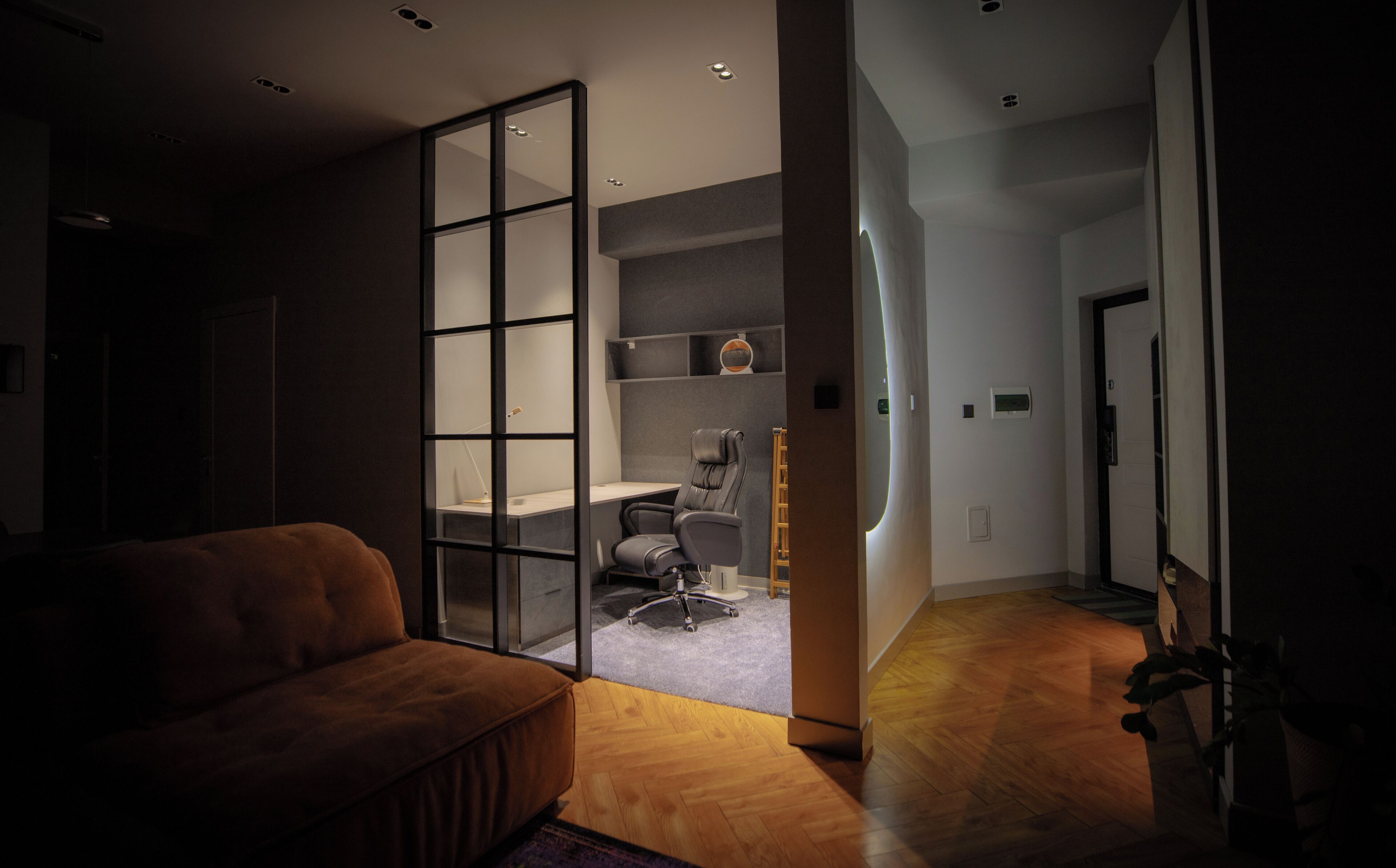 Ein modernes Interieur mit einem Sofa, einem Schreibtisch mit Stuhl und einem Bücherregal.