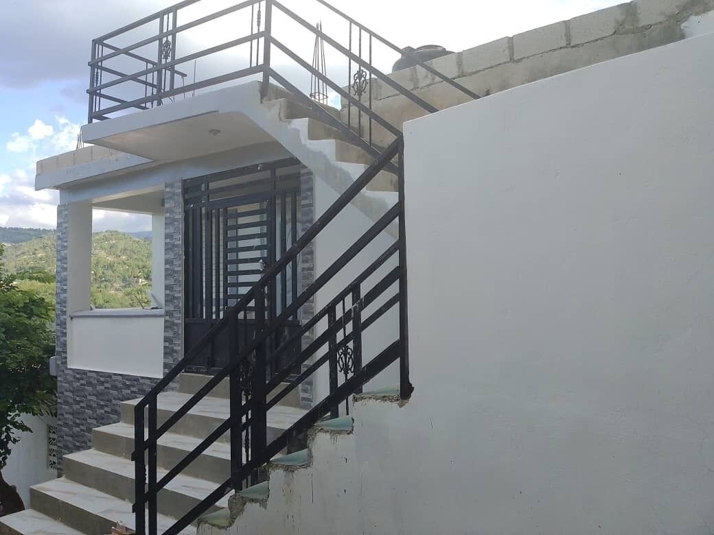 Un escalier avec une rampe métallique menant à une porte.