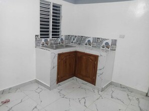 Una cocina con un mueble de esquina, una ventana con persianas y un salpicadero azulejado.