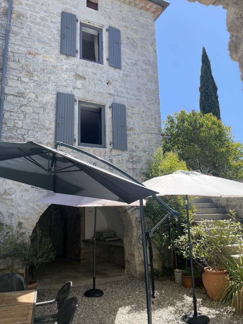 Un edificio in pietra con una zona salotto esterna coperta, una scala e piante in vaso.