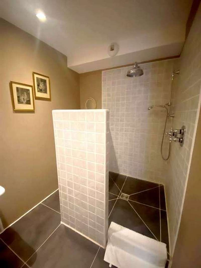 Une salle de bain avec une douche, des murs carrelés et des toilettes.