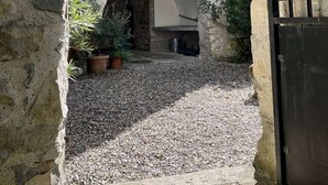 A stone building with a window and shutters, an arched doorway, and a gravel courtyard. - CHARMING, air-conditioned house with a private, fully secured saltwater pool. (Chandolas)