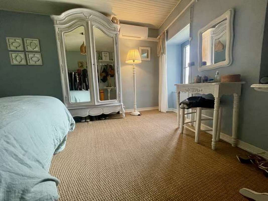 Une chambre à coucher avec un lit, une commode, un miroir et une lampe.