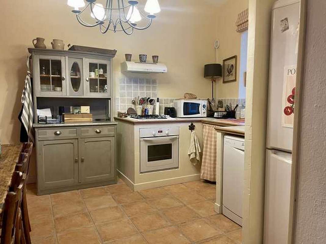 A kitchen with a stove, microwave, cabinets, and a refrigerator.