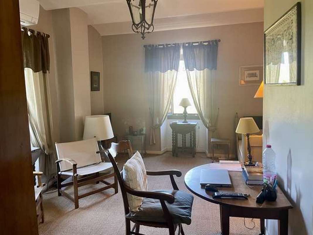 Une chambre d’hôtel avec un canapé, une table ronde, une lampe et une fenêtre avec des rideaux.