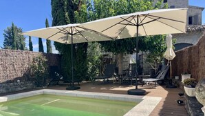 A swimming pool with a wooden deck and a covered seating area. - CHARMING, air-conditioned house with a private, fully secured saltwater pool. (Chandolas)