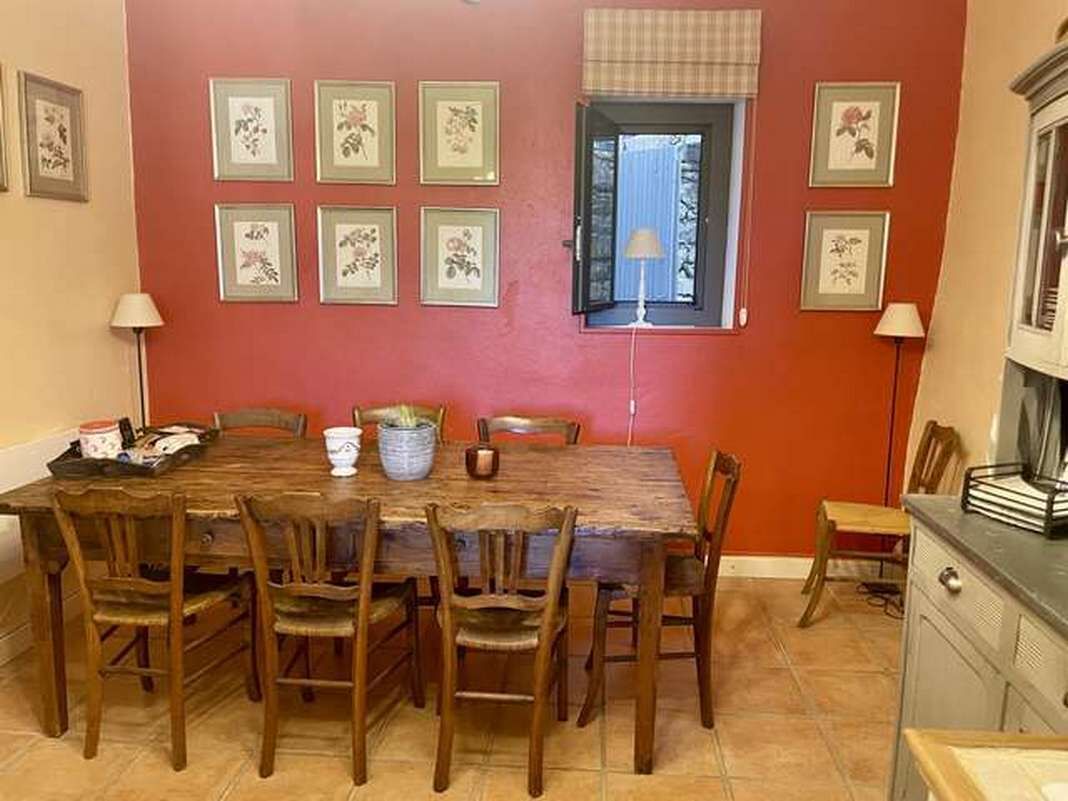 Un'area pranzo con un tavolo e sedie in legno, circondata da quadri floreali appesi alle pareti.