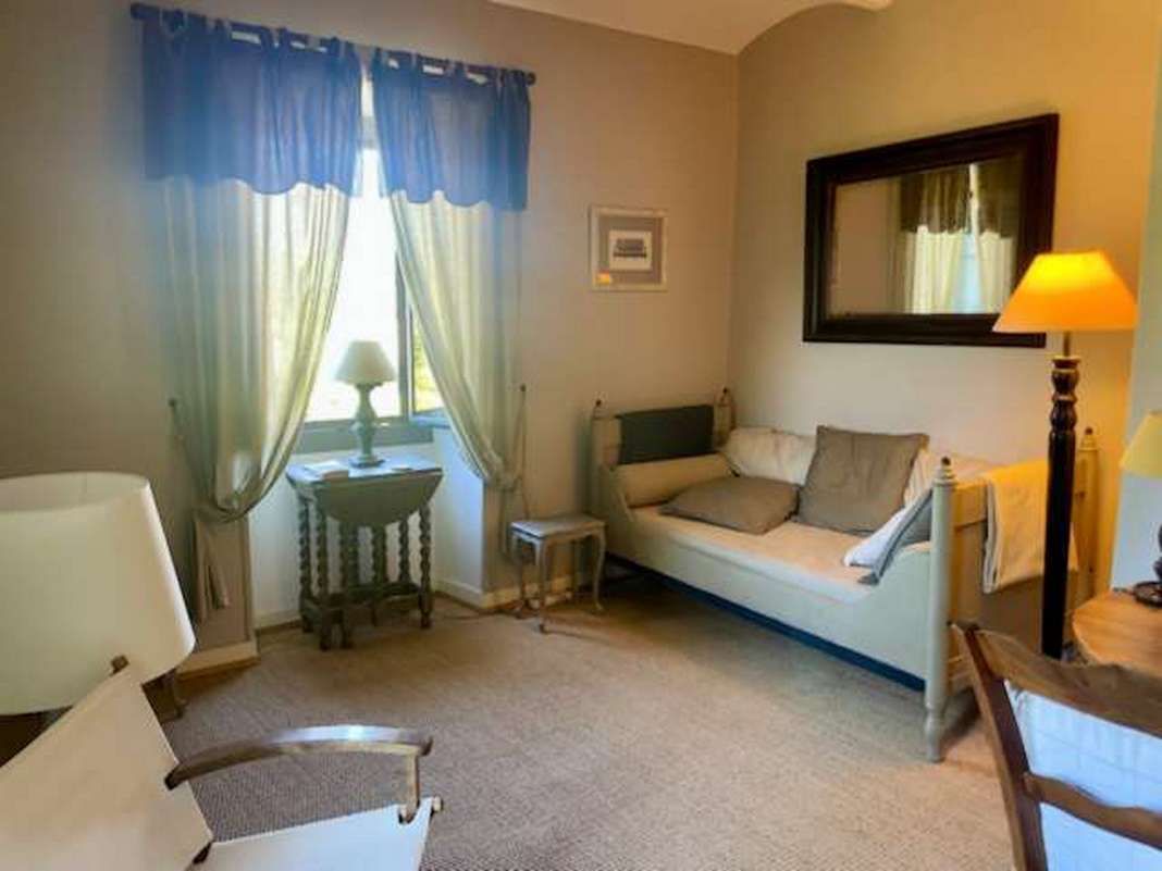 A room with a sofa, a small table, a lamp, and a chair.