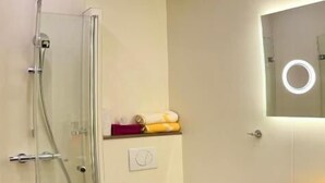 Ein modernes Badezimmer mit Duschkabine aus Glas, Toilette und Waschbecken mit Spiegel.