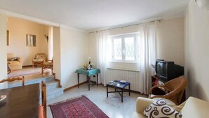 Ein Wohnzimmer mit Sofa, Couchtisch, Fernseher und einem Essbereich mit Tisch und Stühlen.