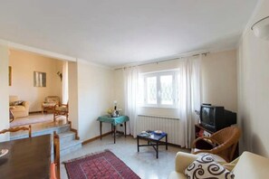 A living room with a sofa, a coffee table, a television, and a dining area with a table and chairs. - Villetta Angela: a villa with a garden a couple of kilometers from the sea (Pietrasanta)