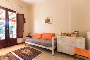 A bedroom with a bed, a dresser, a window with curtains, and a framed picture on the wall. - Villetta Angela: a villa with a garden a couple of kilometers from the sea (Pietrasanta)
