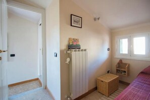 A bedroom with a radiator, a basket, a bed, and a window. - Villetta Angela: a villa with a garden a couple of kilometers from the sea (Pietrasanta)