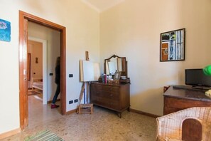 A room with a wooden door, a dresser, a mirror, and a television. - Villetta Angela: a villa with a garden a couple of kilometers from the sea (Pietrasanta)