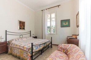 A bedroom with a bed, a dresser, a window with curtains, and a wall with a framed picture. - Villetta Angela: a villa with a garden a couple of kilometers from the sea (Pietrasanta)