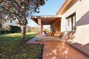 A covered patio with outdoor furniture, a brick pathway, and a building with a window. - Villetta Angela: a villa with a garden a couple of kilometers from the sea (Pietrasanta)