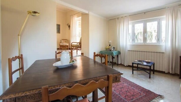 Ein Essbereich mit Holztisch, Stühlen, einer Lampe und Blick auf einen Garten durch ein Fenster.