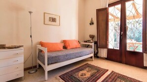 Ein Schlafzimmer mit Bett, Schminktisch, einem Fenster mit Vorhängen und einer Tür.