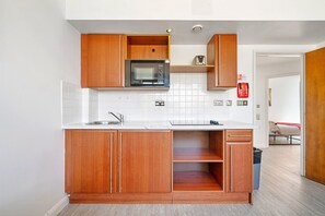 A compact kitchen with wooden cabinets, a built-in microwave, and a sink. - Apartment in South Kensington (London)