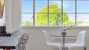 Een moderne eetruimte met een tafel en stoelen, een raam met uitzicht op bomen, en een vaas met bloemen.