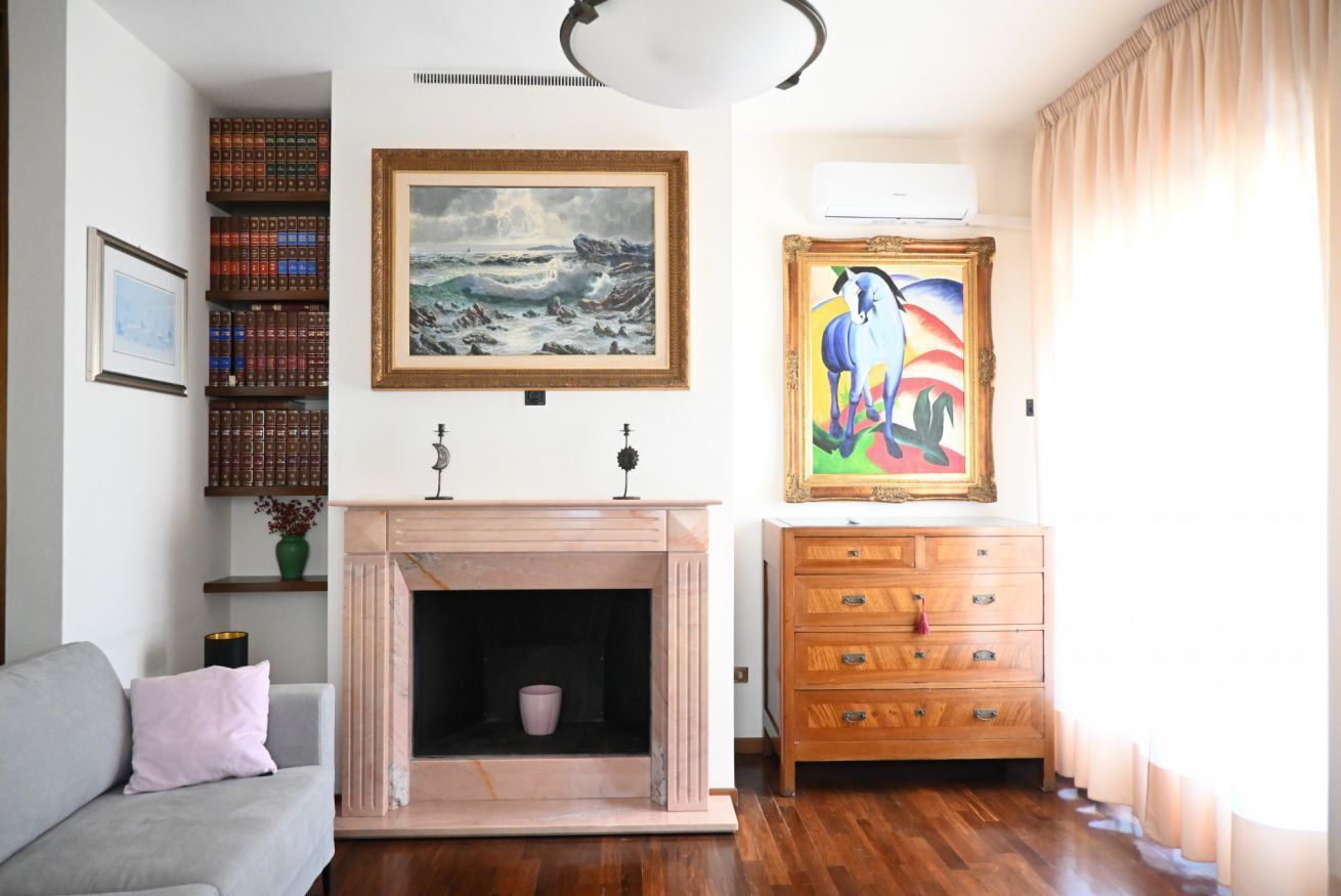 A living room with a fireplace, bookshelves, a sofa, and artwork on the walls.