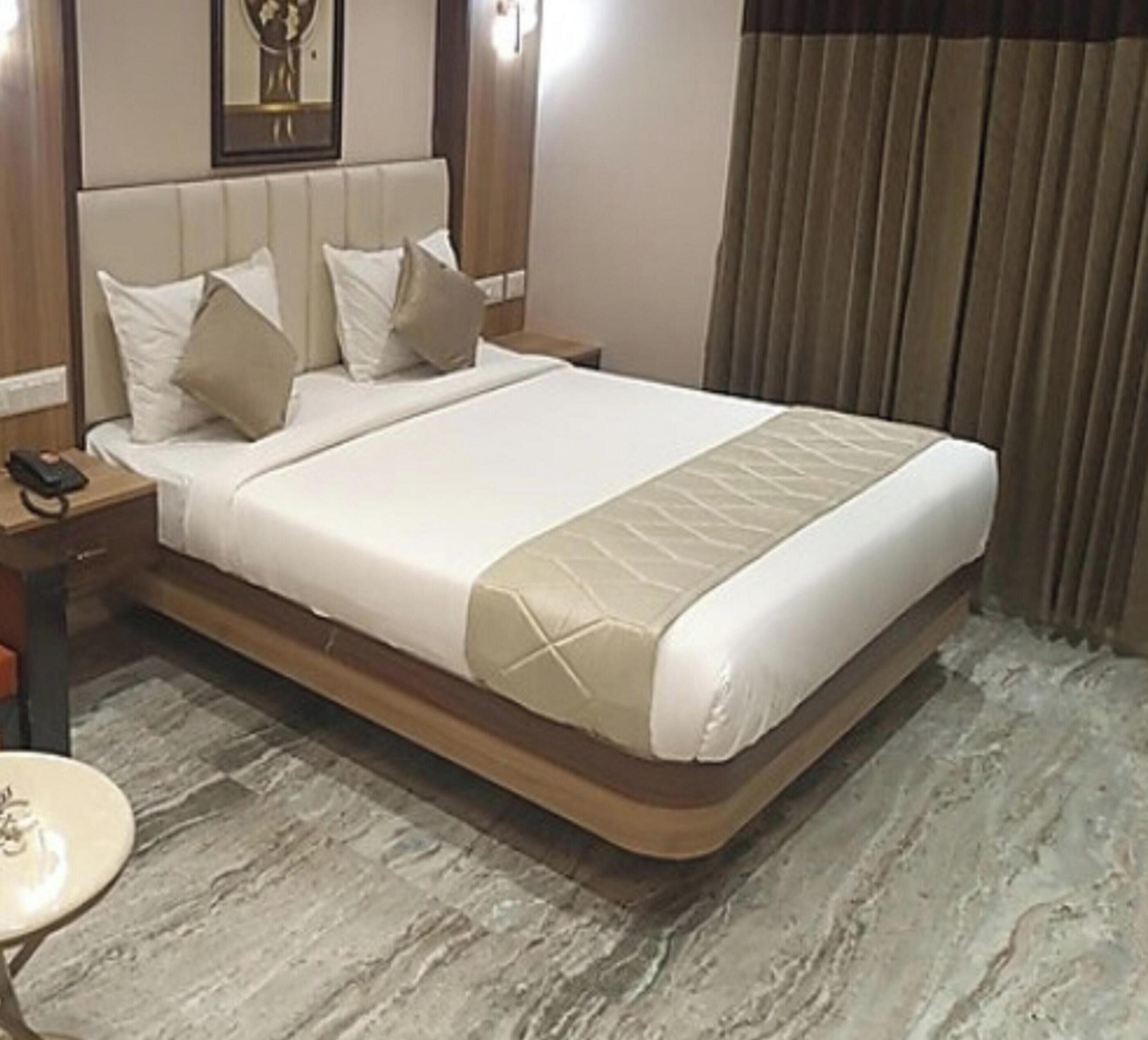 Una camera d'albergo con un letto grande, un comodino, una lampada e una tenda.