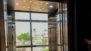 A glass elevator door with a view of a street and buildings outside.