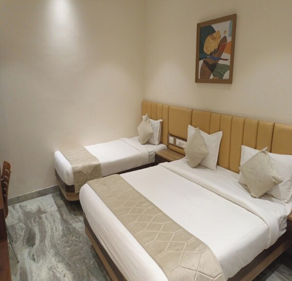 Two single beds with headboards, a wooden chair, and a painting on the wall.