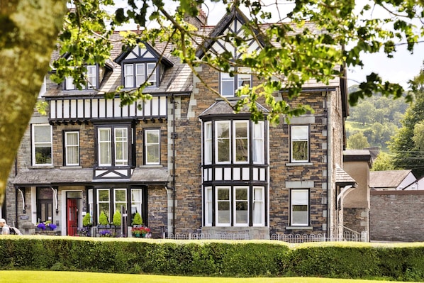 A traditional stone and timber-framed building with multiple windows and a well-maintained hedge in front. - Room Near Lake Windermere (Ambleside)