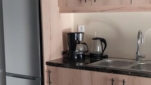 Uma cozinha com armários de madeira, uma geladeira de aço inoxidável, uma cafeteira e uma pia.