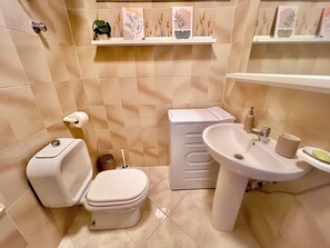 A bathroom with a toilet, bidet, sink, and shelves with decorative items. - Da.Ma's Apartment on the Beach: Modern beachfront apartment with private garage (Giardini Naxos)